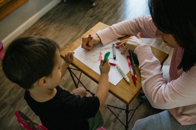 Accueillante familiale de jour réalisant une activité d'éveil et de dessin avec un jeune enfant