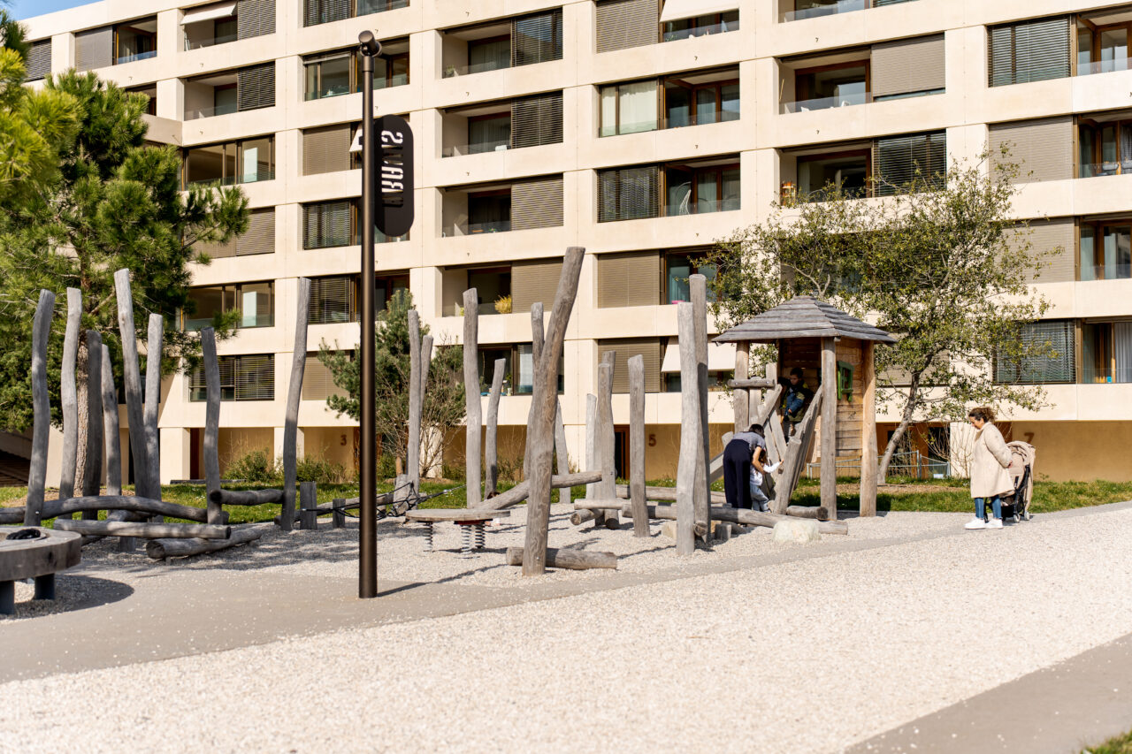 Espace de jeux sécurisé avec structures en troncs d'arbres et cabane au cœur de l'écoquartier Belle-Terre Thônex.