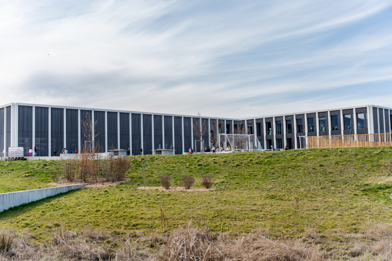 Préau et terrain de sport de l'école de Belle-Terre à Thônex bordés par un espace vert.