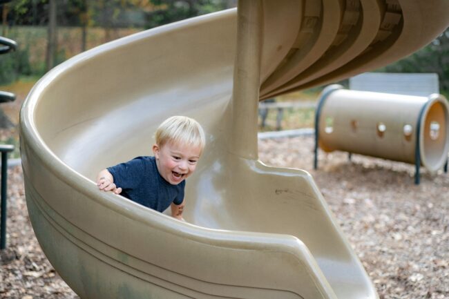 Enfant s'amusant sur un toboggan en spirale dans un parc pour enfants de l'écoquartier Belle-Terre à Thônex